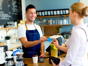 Una mujer paga con tarjeta en una cafetería