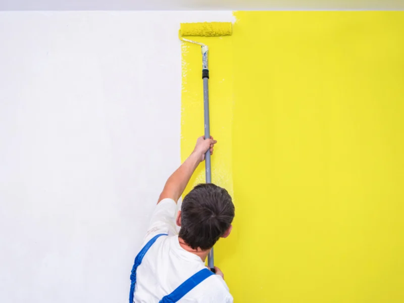 Un pintor pinta de amarillo una pared