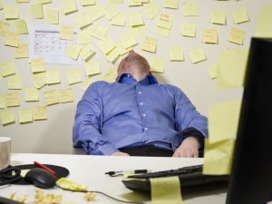 Un hombre se queda dormido con la pared llena de post its