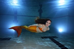 Una mujer vestida de sirena nada bajo el agua