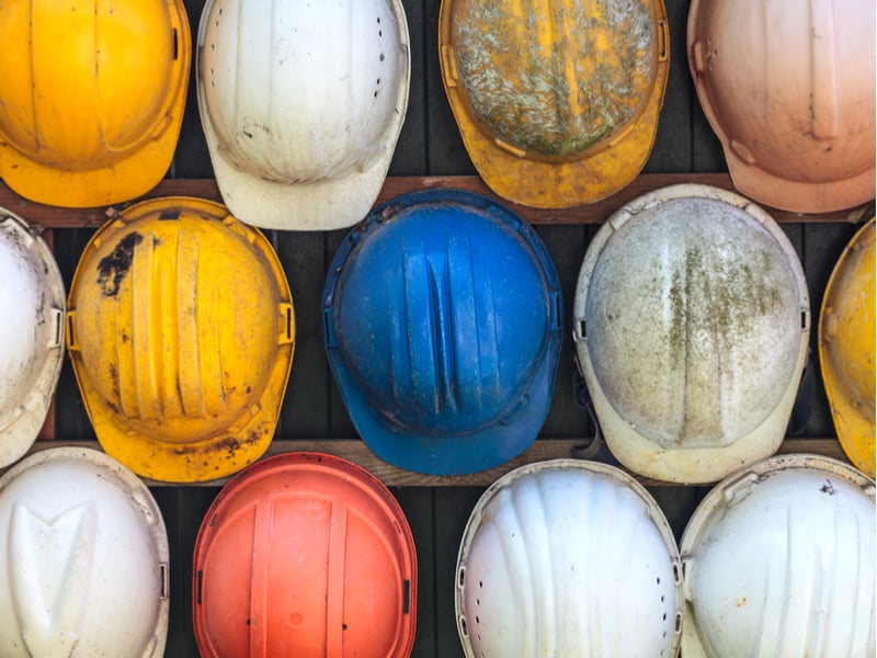 trois rangées de casques de chantier de couleurs différentes