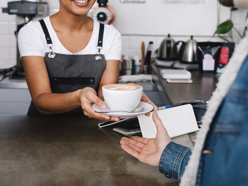 photo d'une serveuse tendant un café à un client par dessus un bar