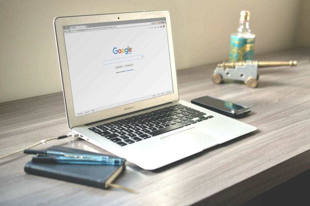 A laptop on a desk open to a blank Google Search