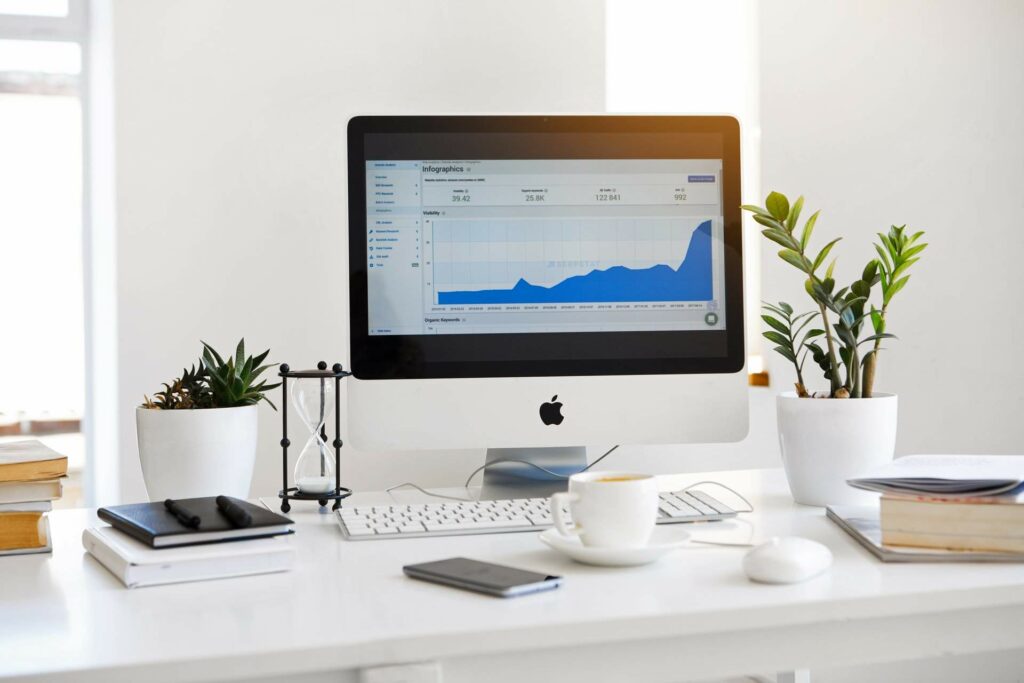 A computer on a desk showing a line graph depicting website traffic