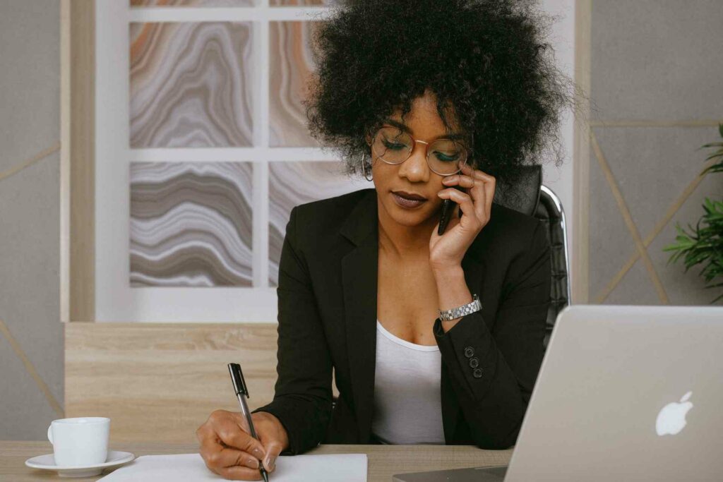 A woman sitting at her desk working on improving her business reputation on the phone and on a laptop