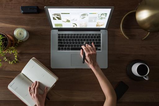 Person looking at images and adjusting planner while working at a computer.