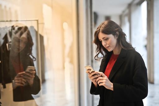 A woman in a black coat looking at a website on her smartphone