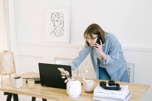 A woman talking on the phone and answering an email at her desk