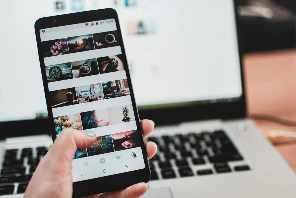 A person using instagram in front of a laptop computer