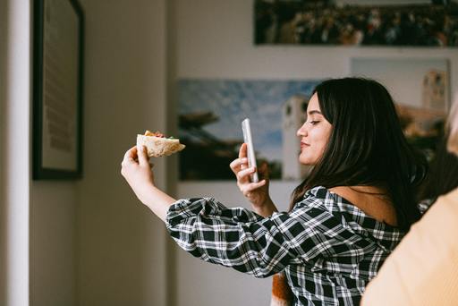 An influencer taking a picture of a local Pizza