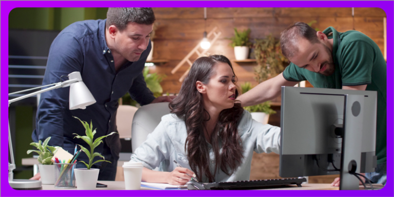 Two men and a woman on a desk looking at a computer