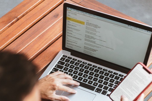 Man checking an email on a laptop as well as his mobile phone