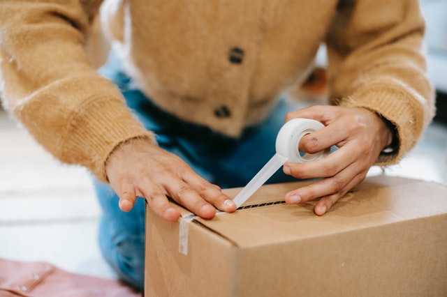 A woman boxing up one of her craft sales to ship it out.